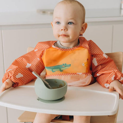 Bavoir manche longue imperméable dans le cou de bébé assis dans chaise haute
