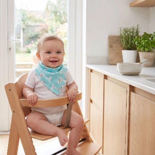 Bavoir bébé autour du cou de bébé assis dans sa chaise haute dans la cuisine