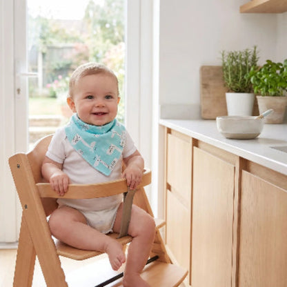 Bavoir bébé autour du cou de bébé assis dans sa chaise haute dans la cuisine