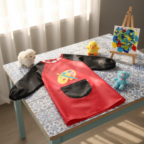 Bavoir imperméable rouge sur la table avec une peinture sur le spport pour peindre avec peluches sur la table