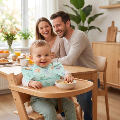Bavoir bébé imperméable avec poche verte autour du cou de bébé assis dans sa chaise haute