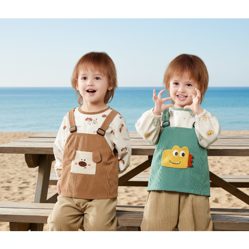 Bavoir bébé imperméable les jumeaux porte ils sont assis à la table de pique nique près de la plage