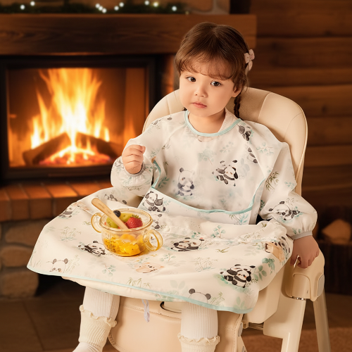 Bavoir imperméable bébé motif panda assis dans sa chaise haute près du foyer