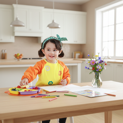 Bavoir manche longue imperméable jaune orange petite fille assis a la table en train de bricolé et manger