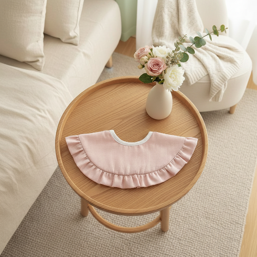 Bavoir nouveau né dentelé rose sur la table dans la chambre à coucher