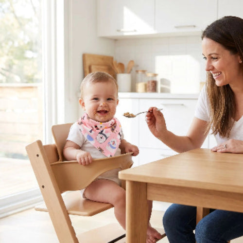 Bavoir bandana coton dans le cou de bébé assis dans sa chaise haute et maman lui donne a manger