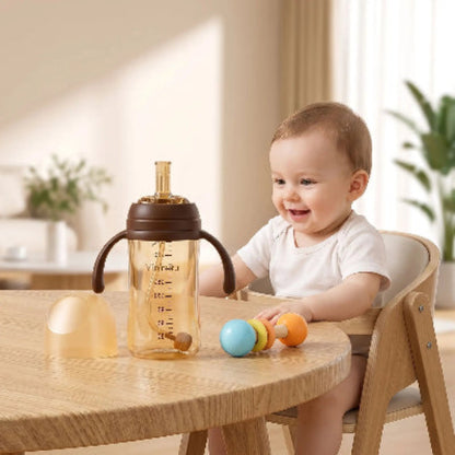 Biberon de 240ml avec paille sur la table de cuisine avec bébé et jouet coloré