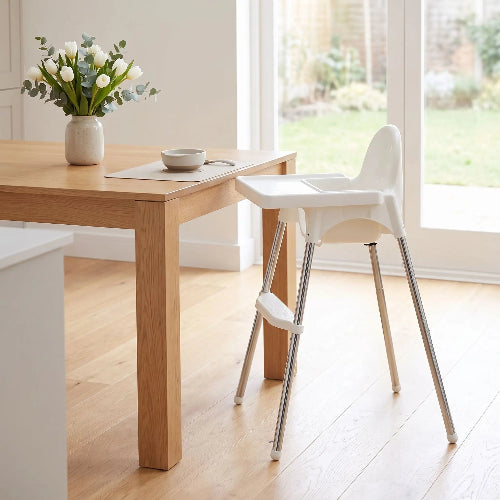 Chaise haute bébé prêt de la table de cuisine avec bouquet de fleurs blanches