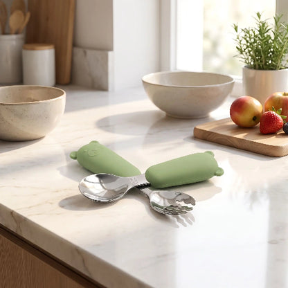Couvert bébé​ Ergonomique vert sur le comptoir de cuisine avec fruits à coté