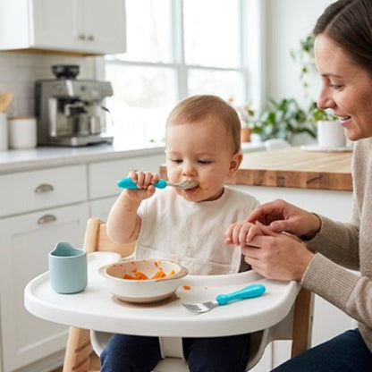 Couvert pour bébé manches bien arrondies turquoise sur la tablette de la chaise haute