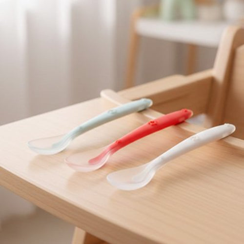 Cuillère bébé trois diferentes couleurs sur la chaise haute de bébé 