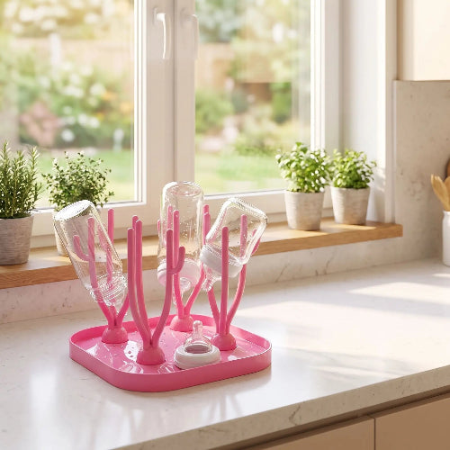 Egouttoir biberon rose sur le comptoir de la cuisine près d'une fenêtre lumineuse