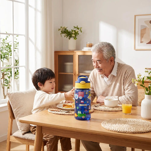 Gobelet paille bébé aquasafe jaune bleu foncé sur la table de cuisine avec l'enfant et grand papa