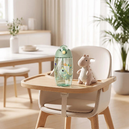 Gobelet paille bébé dinosafe vert sur la chaise haute de bébé dans la cuisine