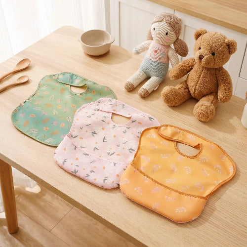 Lot de bavoir bébé vert olive rose brun sur la table de cuisine