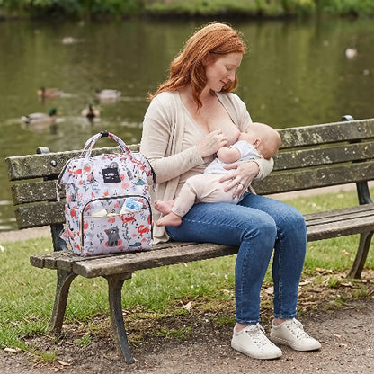 Sac a langer bébé nomade multipoches avec bébé et maman assis sur le banc 