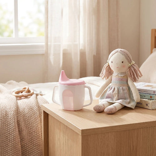 Tasse d'apprentissage bébé ergonomique anti fuite rose sur la table de chevet de bébé
