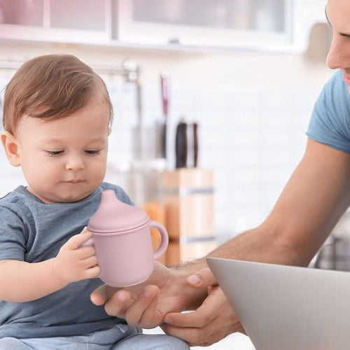 Verre bébé rose pâle dans les mains de bébé